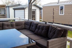 ein Sofa auf einem Balkon mit einem Tisch in der Unterkunft Zee&Zout, chalet 6 pers. bij Renesse en strand! in Renesse