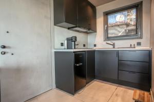 eine Küche mit schwarzen Schränken und einem Fenster in der Unterkunft Meteora Heaven and Earth premium suites - Adults Friendly in Kalambaka