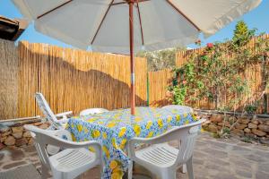 a table and chairs with an umbrella on a patio at San Teodoro Holiday House A in San Teodoro