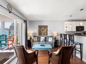 a living room with a couch and a table and chairs at Laid Back By The Sea - Steps from the beach with amazing ocean views, Parking for 2 included, condo in Carolina Beach
