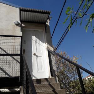 una puerta blanca en el lateral de un edificio con escaleras en Rita, en Concepción del Uruguay