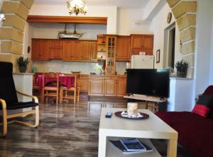 a living room with a couch and a tv and a kitchen at Aegina town, summer house in Egina