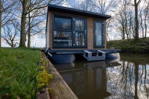 a tiny house on a boat in the water at Waterlodges WeidumerHout in Weidum