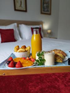 a tray of food with fruit and a bottle of orange juice at Villa Montês Guesthouse in Coja