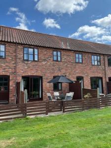 a brick house with a table and chairs and an umbrella at Gatekeeper Cottage in Norwich