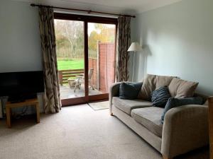 a living room with a couch and a sliding glass door at Gatekeeper Cottage in Norwich