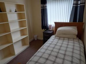 a bedroom with a bed and shelves and a window at Inviting light and airy 3-Bed Apartment in Wick in Wick