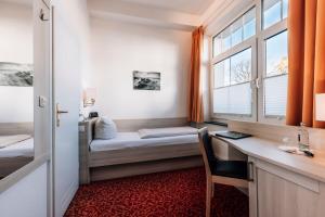 ein Zimmer mit Schreibtisch, Bett und Fenster in der Unterkunft Hotel Gorch Fock in Timmendorfer Strand