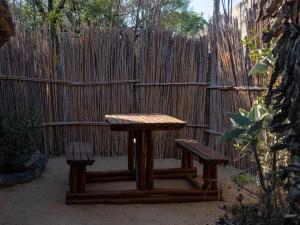 a picnic table and two benches in front of a fence at African Sky Bush Camp in Rabelaisruskamp