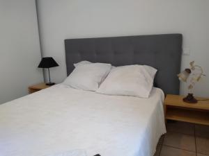 ein Schlafzimmer mit einem weißen Bett mit einem grauen Kopfteil in der Unterkunft "Les Balcons 2" -T2-balcons-Garage privé optionnel-Centre historique & plages à 21km ! in Pézenas