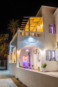 a white building with a balcony with lights on it at SantoriniNY in Perissa