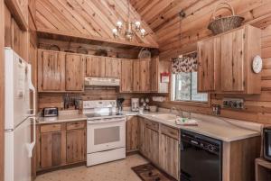 - une cuisine avec des placards en bois et un réfrigérateur blanc dans l'établissement Breakaway Cabin, 3 Bedrooms, Sleeps 6, Pets Welcome, Wood Fireplace, à Ruidoso