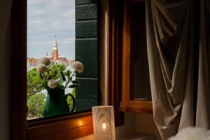 a vase of flowers in a window with a view at Hideaway Biennale in Venice