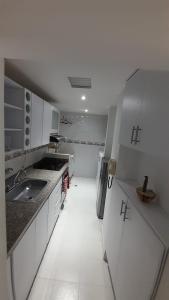a white kitchen with a sink and a refrigerator at Aparta suit Rodadero in Gaira