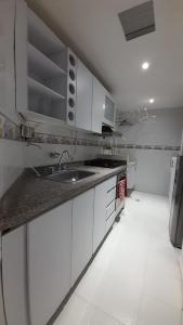 una cocina con armarios blancos y fregadero en Aparta suit Rodadero, en Gaira