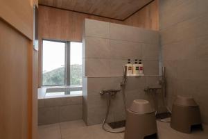 a bathroom with a shower and a toilet and a window at Gardenvilla Shirahama in Shimoda