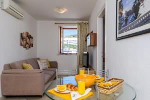 un soggiorno con divano e tavolo in vetro di Orka Apartments a Dubrovnik