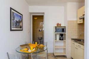a small kitchen with a glass table with chairs at Orka Apartments in Dubrovnik