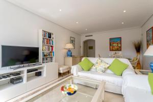 een woonkamer met een witte bank en een tv bij Beautiful penthouse with solarium in Benahavís