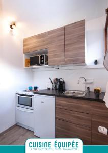 a kitchen with wooden cabinets and a sink at BRIANCON - SERRE CHEVALIER 1200 - Joli Appartement - Face aux Pistes en Centre Ville in Briançon