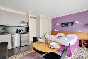 a kitchen and a living room with a table and a bed at CMG - Cosy & charmant appartement Paris in Issy-les-Moulineaux