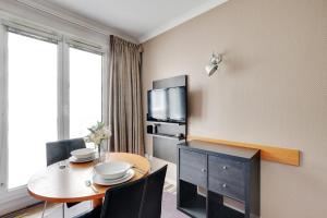 a hotel room with a table and a tv at CMG - Cosy & charmant appartement Paris in Issy-les-Moulineaux