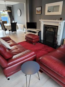 a living room with a red leather couch and a fireplace at Anchor, Dunfanaghy in Dunfanaghy