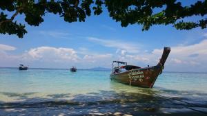 a boat sitting in the water on the beach at Phi Phi Relax Beach Resort in Phi Phi Islands