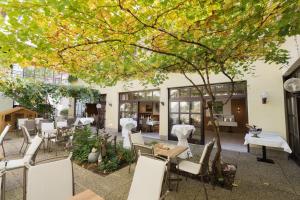 a patio with white chairs and tables and a tree at Gasthof-Restaurant Kollar Göbl in Deutschlandsberg