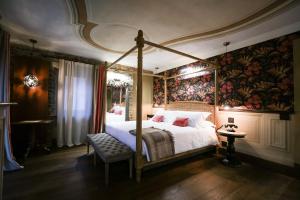 sypialnia z łóżkiem z baldachimem i malowidłem ściennym w obiekcie La Piazzetta degli Artisti - Boutique B&B w mieście Bossolasco
