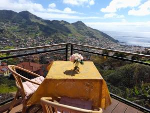 una mesa con un jarrón de flores en el balcón en Casa da Adega, en Machico