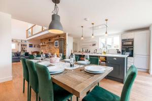 a kitchen and dining room with a wooden table and green chairs at The Old School Hall - Opulence And Location in Kent
