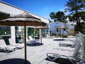 a group of chairs and umbrellas on a patio at Vent d'Eden Park Hôtel in Saint-Hilaire-de-Riez