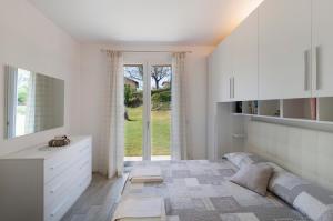 a white bedroom with a bed and a window at Appartamento Zerboni C1 in Lenno