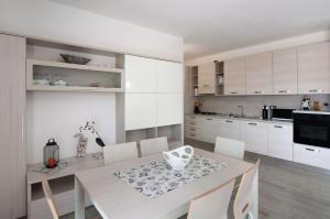 a kitchen with a white table and white cabinets at Appartamento Zerboni C2 in Lenno