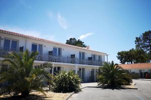 un edificio blanco con palmeras delante en Vent d'Eden Park Hôtel en Saint-Hilaire-de-Riez