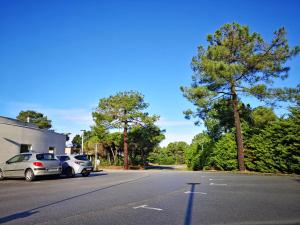 a parking lot with two cars parked next to a building at Vent d'Eden Park Hôtel in Saint-Hilaire-de-Riez