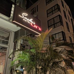a hotel sign and a palm tree in front of a building at Sacha's Hotel Uno SHA in Bangkok