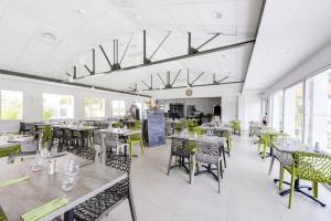 a dining room with tables and chairs and windows at Vent d'Eden Park Hôtel in Saint-Hilaire-de-Riez