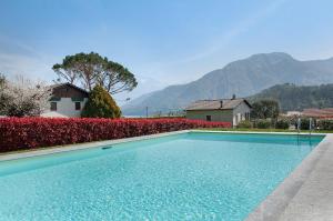 a swimming pool in front of a house with mountains at Appartamento Zerboni C1 in Lenno