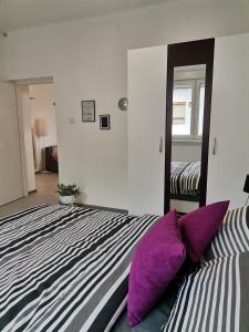 a bedroom with a bed with purple pillows and a mirror at Apartman Maki in Sombor