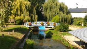 a bridge over a river in a park at Le gite du Mont in Val Couesnon