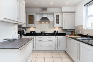 a kitchen with white cabinets and black counter tops at Merlins in Hayle