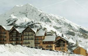 a large building in front of a snow covered mountain at Appartement aux pieds des pistes in Valmeinier