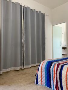 a bedroom with gray curtains and a bed and a window at Pousada Chalés Praia Vermelha in São João Batista do Glória