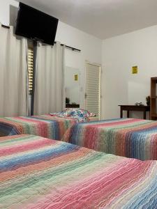 two beds in a room with a flat screen tv at Pousada Chalés Praia Vermelha in São João Batista do Glória