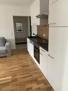 a kitchen with white cabinets and a wooden floor at Quality See Apartments Reifnitz in Reifnitz