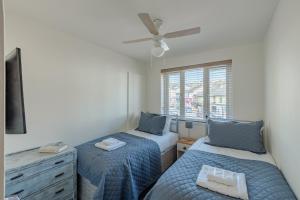 Two Bed Apartment Bowness-On-Windermere 2022Refurb في باونيس أون وينديرمير: غرفة نوم بسريرين ومروحة سقف