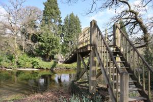 a wooden bridge over a stream in a park at HEDDFAN, Luxury 3 bedroom timber lodge, Now with WiFi, Caer Beris Holiday Park, Builth Wells in Builth Wells