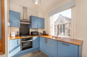a kitchen with blue cabinets and a large window at Patrick's Pool- 4 Bedroom,4 Bathroom, Most Central Luxury Townhouse! in York